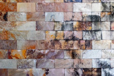 Textured stone wall with multicolored natural slate tiles.