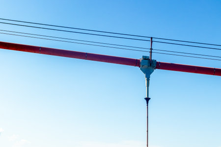 Irrigation system with red pivot arm against clear blue sky.
