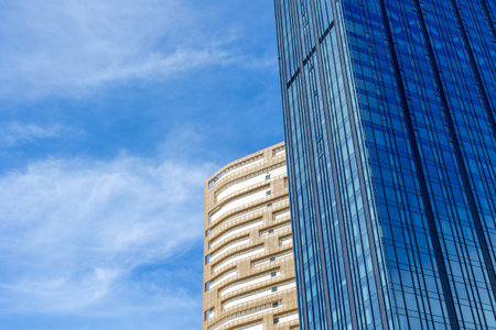 Modern architectural contrast with glass and stone skyscrapers under blue sky.