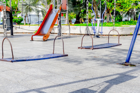Empty playground swings and slide in park setting.