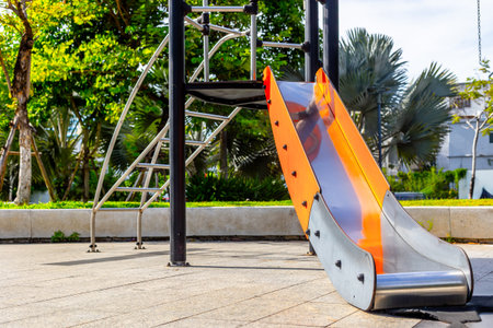 Empty playground slide in sunlit park with greenery and trees.の写真素材