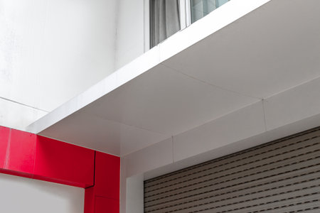 Modern architectural detail with red accent and metal roller shutter.