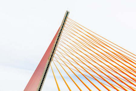 Modern geometric bridge with orange cables against a clear sky.の写真素材
