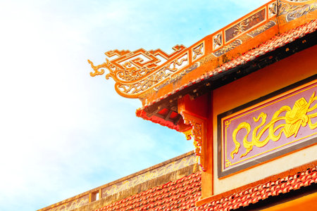 Traditional Asian temple roof against clear blue sky with intricate architectural details.の写真素材