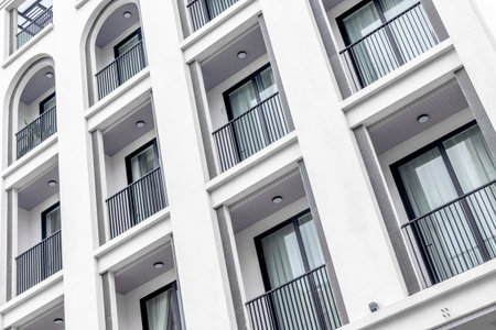 Modern white apartment building with balconies and large windows.の写真素材