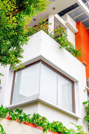 Modern urban building with white exterior and lush greenery.の写真素材