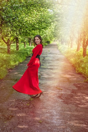 Young girl in red dress dancing in the parkの写真素材