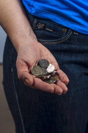 Woman in the blue t-shirt and jeans holds a handful of coins, russian rubles. Focus on coins.の写真素材
