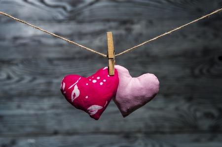 Two hearts together with clotherspin on linen rope on wooden rustic background. Horizontal view. Valentine's theme.の写真素材