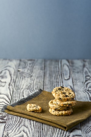 Homemade cookies with cheese, olives and rosemary on linen napkin on wooden rustic background. Focus on stack. Vertical view.の写真素材