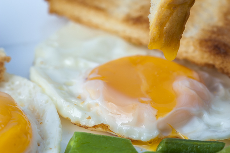 Close up of fried eggs, green beans with piece of toast on white plate. English breakfast. Horizontal view.の写真素材