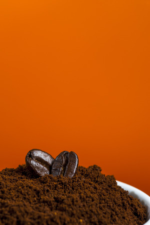 Coffee beans and ground coffee on orange background.の写真素材