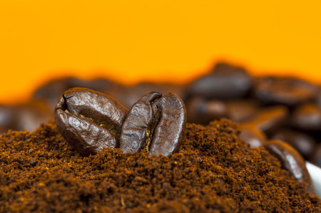 Coffee beans and ground coffee on orange background.の写真素材