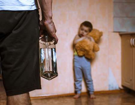 Drunk father and frifhtened child with toy bear. Domestic violence.の写真素材