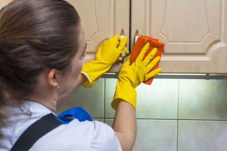Female janitor scrubbing the kitchen cupboard with a rag. Housework and cleaning.の写真素材