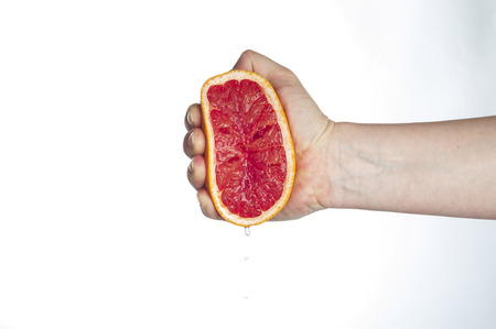Female hand squeezing grapefruitの写真素材