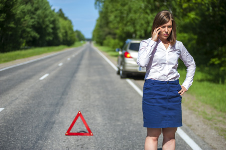 Young woman standing on the road after breakdown and calling to a car assistance.の写真素材