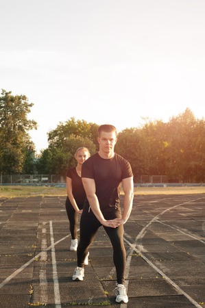 Young caucasian healthy couple doing lunges. Fitness or running workout outdoors.の写真素材