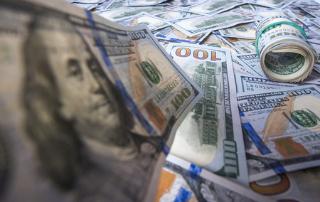 One hundred dollar bill on the background of dollar heap