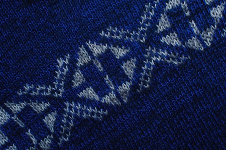 Blue knitted woolen fabric texture with white ornaments for wallpaper or an abstract background.の写真素材