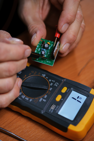 Male electrician checking microcircuit with multimeter, closeupの写真素材