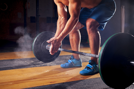 Cropped shot of young male athlete with naked torso clapping hands before barbell training in gym. Power lifting, weightlifting, cross fit equipment. fitness, sports conceptの写真素材