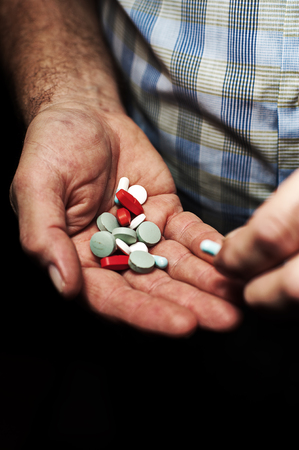 Heap of colorful medical pills in senior male hands, closeupの写真素材
