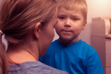 Portrait of young mother and her little son hugging after quarrelの写真素材