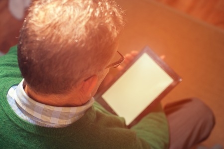 Mature man sitting on sofa and using digital tablet, closeup
