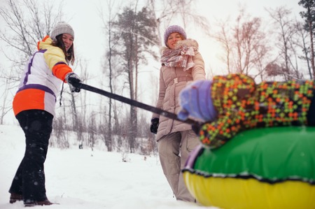 Two women and child sledding on snow tubingの写真素材