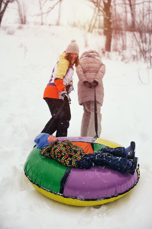 Happy smiling people sledding on snow tubingの写真素材