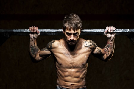 Strong man with naked torso doing pull upsの写真素材