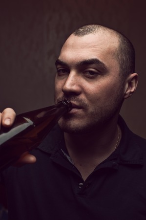 Portrait of young drunk man with beer bottleの写真素材