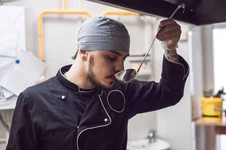 Male chef tasting meal in restaraunt kitchenの写真素材