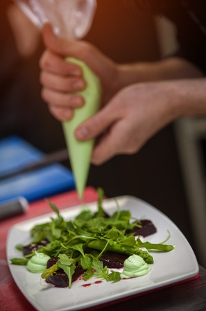 Male chef cooking salad with arugula and beetの写真素材