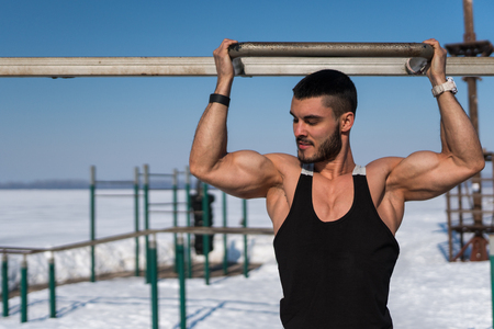 Bodybuilder with sportive body posing outdoors