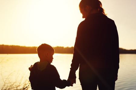 Silhouettes of mother and son watching sunsetの写真素材