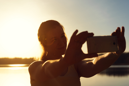 Happy caucasian woman making selfie at sunsetの写真素材