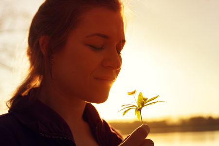 Happy smiling woman smelling forest flowerの写真素材