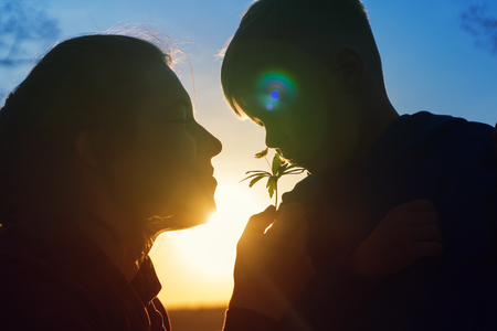 Young woman and her child smelling forest flower.の写真素材