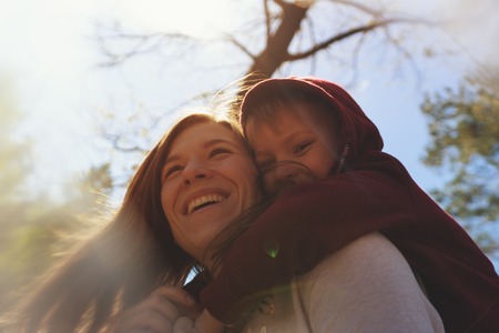 Young woman hugging little son, playing in parkの写真素材