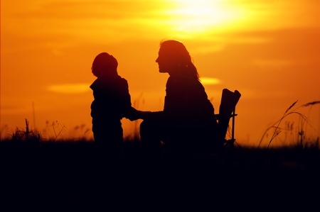 Silhouettes of mother and son at setting sunの写真素材