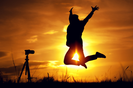 Silhouette of happy female photographing herselfの写真素材