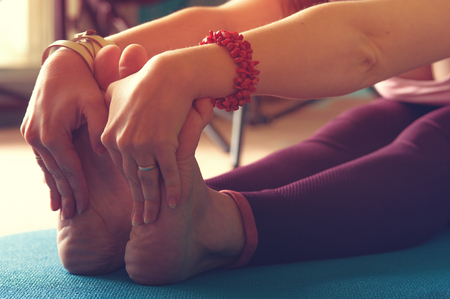Closeup of female legs on exercise mat. Young woman practicing yoga in class. Body balance training. Fitness and healthy lifestyle concept.の写真素材