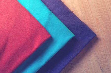 Colorful t-shirts on light wooden table, close up.の写真素材