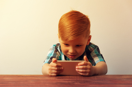 Caucasian kid looking at the smartphone screenの写真素材
