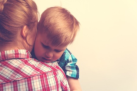 Young mother comforting her little boy. Sad unhappy child hugging his mother. Family relations problems.の写真素材