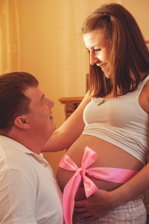 Happy young pregnant couple at homeの写真素材