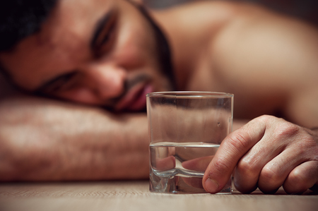 Drunken young man sleeping at the table with glassの写真素材