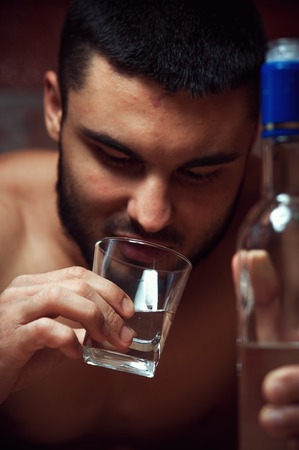 Young drunken man with bottle and glassの写真素材